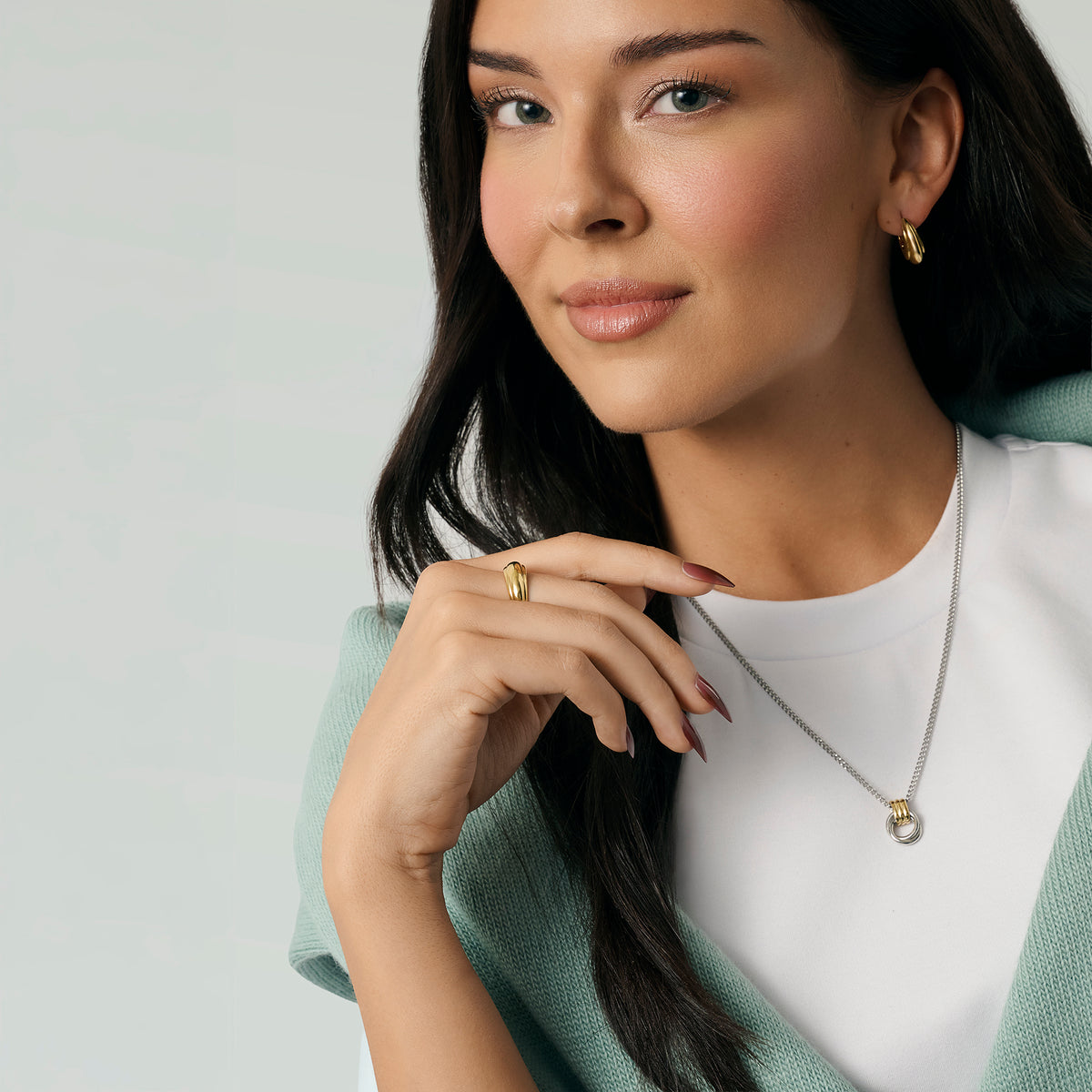 Model wearing a gold dome ring, gold hoop earrings and a silver chain necklace with a two-tone circle pendant, styled with a mint green cardigan and white top on a light background. Nickel-free, waterproof & tarnish-resistant stainless steel jewelry for sensitive skin.

Mannequin portant une bague dôme dorée, des boucles d'oreilles anneaux dorées et un collier à chaîne argentée avec pendentif cercle bicolore, agencés avec un cardigan vert menthe et un haut blanc sur fond pâle. Bijoux en acier inoxydable.